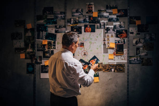 An old detective is looking at photos of suspects in his office